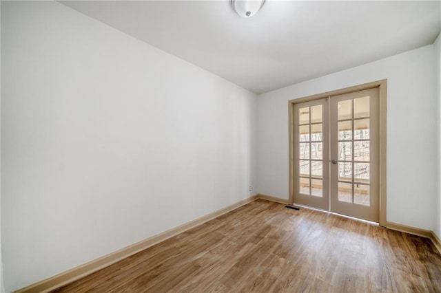 spare room featuring light wood-type flooring, visible vents, baseboards, and french doors