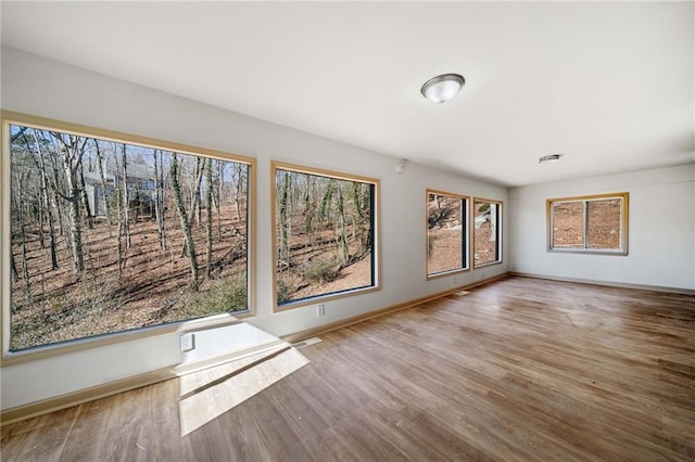 empty room with visible vents, baseboards, and wood finished floors