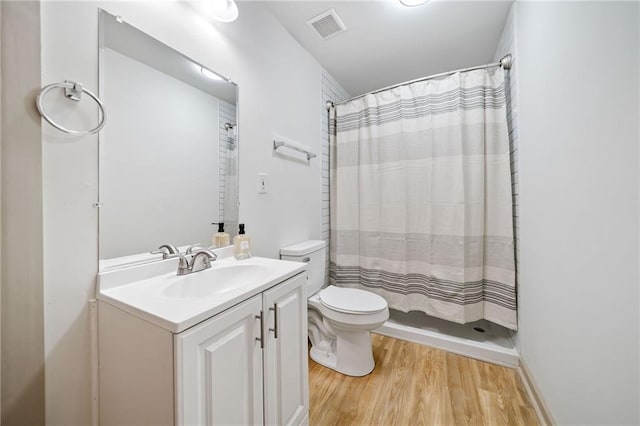 bathroom featuring curtained shower, visible vents, toilet, vanity, and wood finished floors