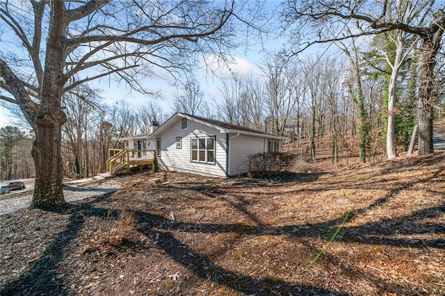 view of property exterior featuring a chimney and a wooden deck