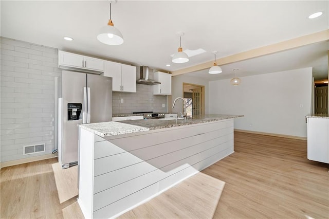 kitchen featuring white cabinetry, light wood finished floors, wall chimney exhaust hood, and appliances with stainless steel finishes