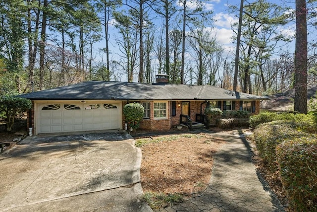 ranch-style house featuring brick siding, driveway, an attached garage, and a chimney