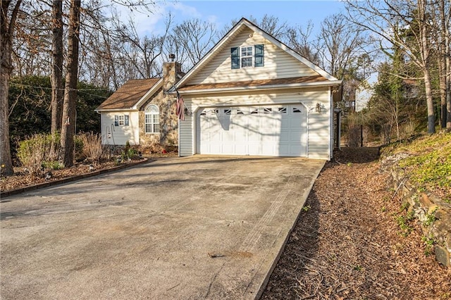 view of front of property with driveway, a chimney, and an attached garage