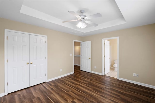 5159 Wellsley Bnd, Alpharetta, GA 30005 - unfurnished bedroom featuring a tray ceiling, baseboards, wood finished floors, and a closet
