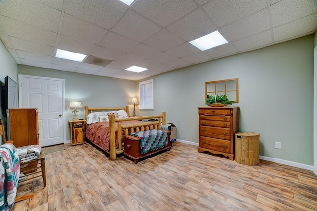 bedroom with a paneled ceiling and light hardwood / wood-style flooring