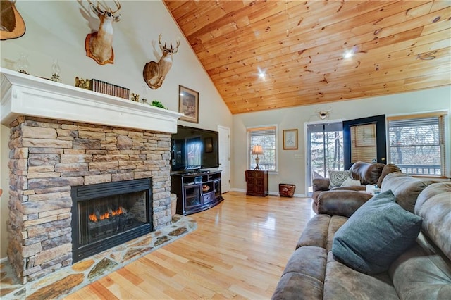 living room featuring wooden ceiling, light hardwood / wood-style floors, high vaulted ceiling, and a stone fireplace