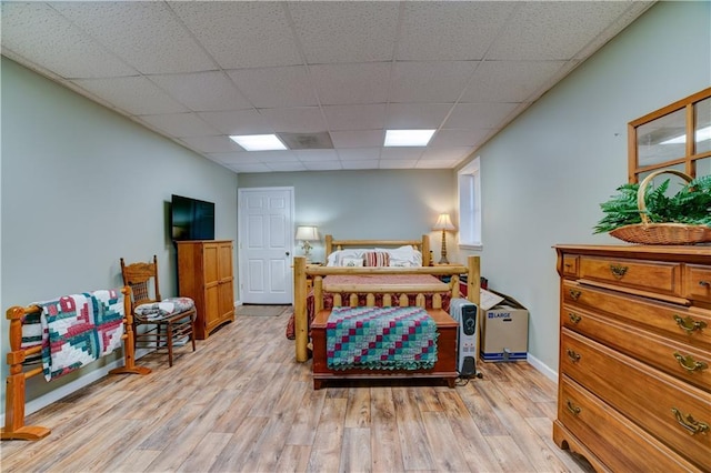 bedroom with light wood-type flooring and a drop ceiling