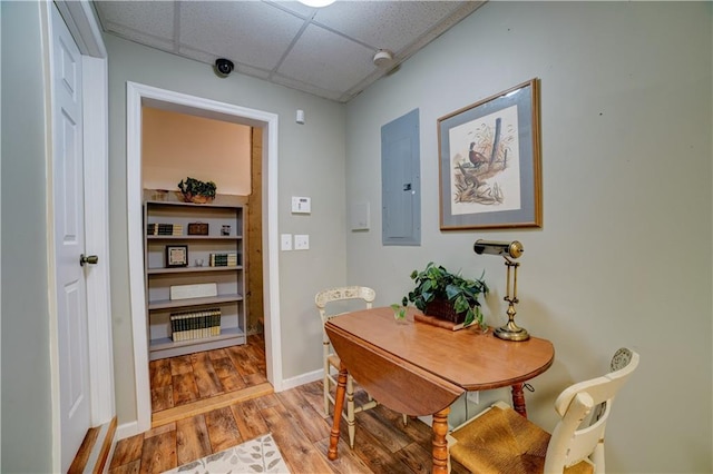 dining space featuring a paneled ceiling, electric panel, and light hardwood / wood-style floors