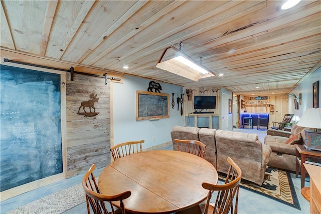 dining room with a barn door, wooden ceiling, and wooden walls