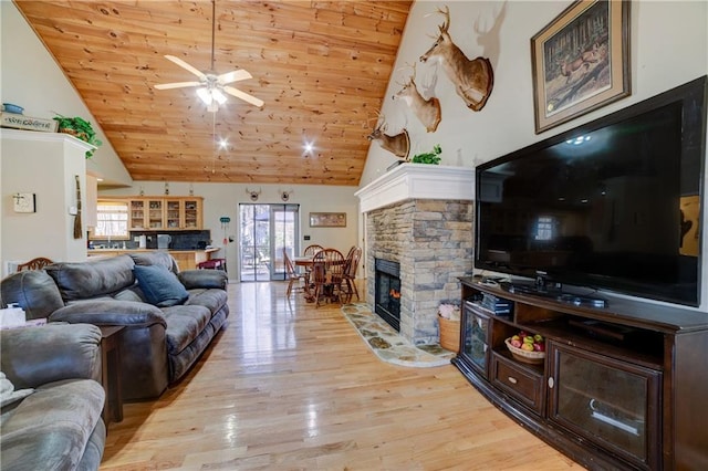 living room with ceiling fan, high vaulted ceiling, wooden ceiling, a fireplace, and light hardwood / wood-style floors