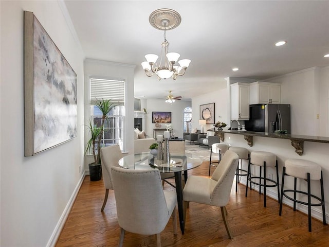 dining area with ceiling fan with notable chandelier, dark hardwood / wood-style floors, and ornamental molding