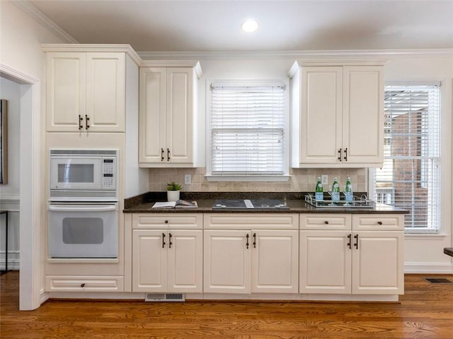 kitchen with hardwood / wood-style floors, white appliances, white cabinetry, and dark stone counters