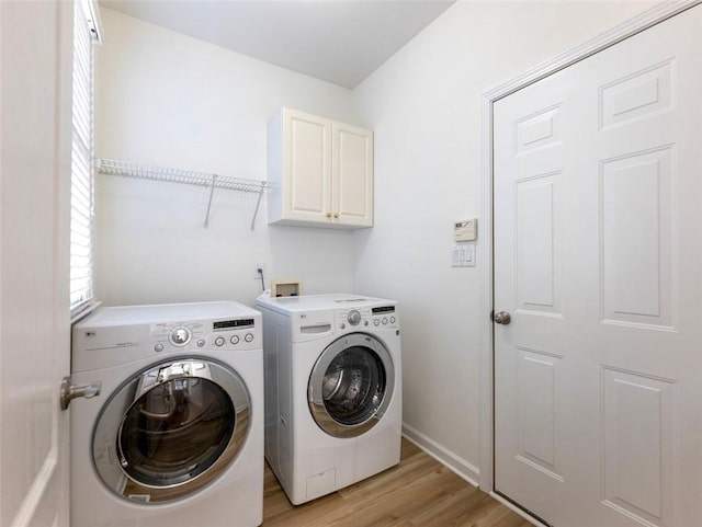 washroom with light wood-type flooring, washing machine and dryer, and cabinets