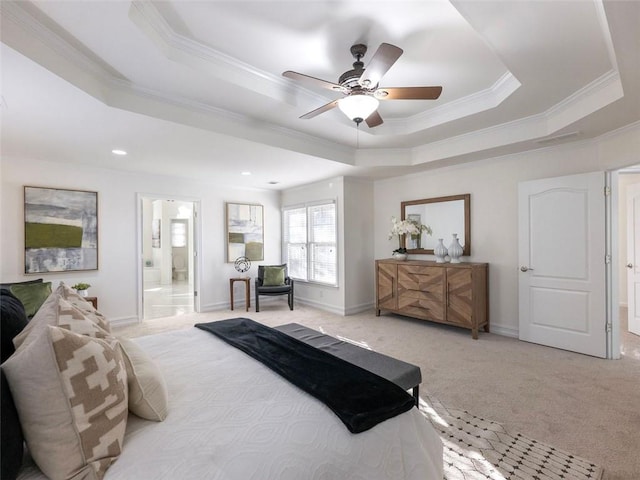 carpeted bedroom with ensuite bath, ceiling fan, ornamental molding, and a tray ceiling