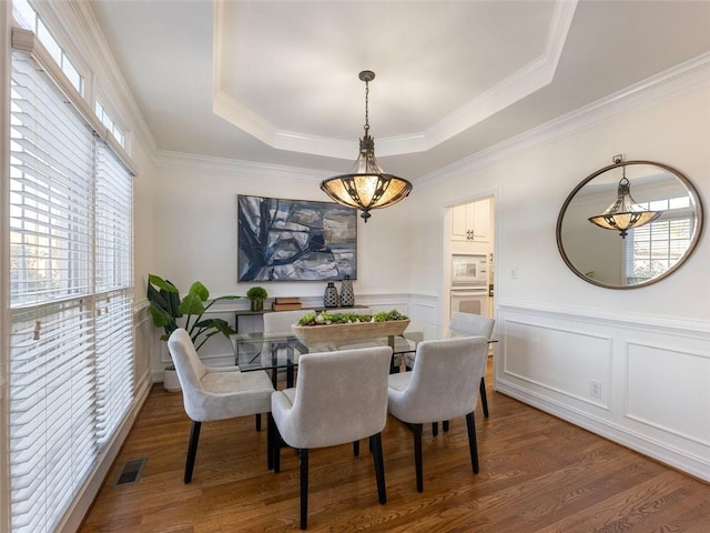 dining space featuring a tray ceiling, dark hardwood / wood-style floors, and ornamental molding