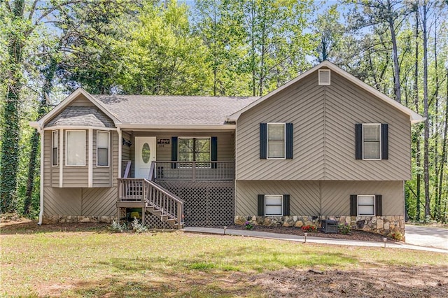 view of front of home featuring stone siding, stairway, a front yard, and covered porch