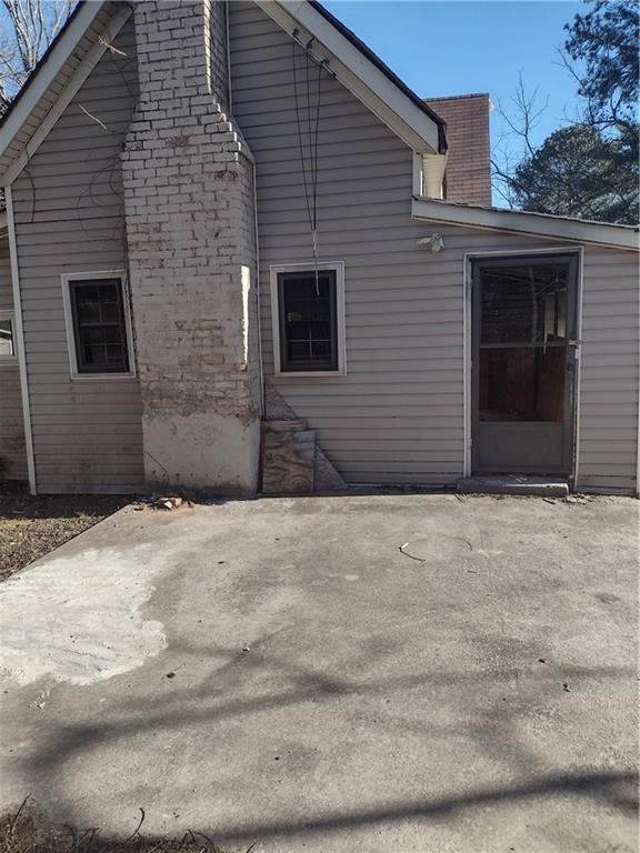 view of side of home featuring a patio area and a chimney