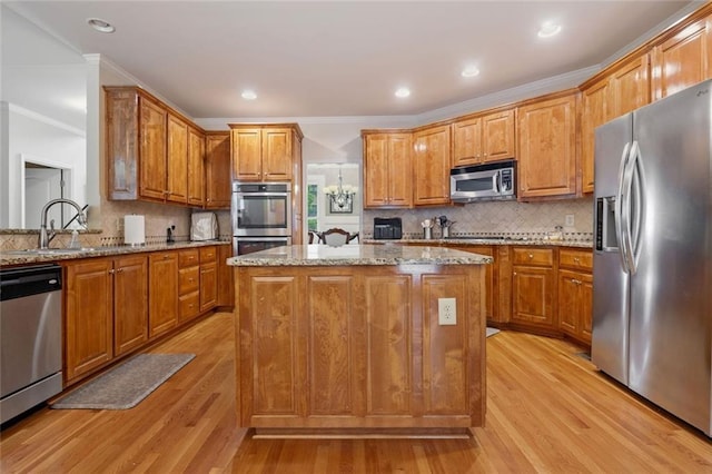 1898 Alcovy Shoals Blf SE, Lawrenceville, GA 30045 - kitchen featuring appliances with stainless steel finishes, light wood-style floors, light stone counters, decorative backsplash, and a kitchen island
