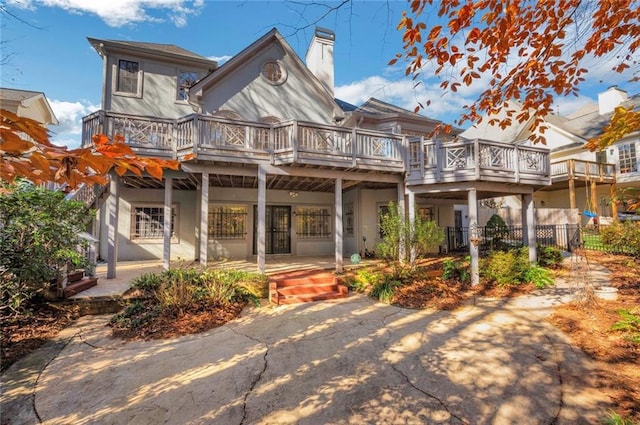 back of property with stucco siding, a porch, a chimney, and fence