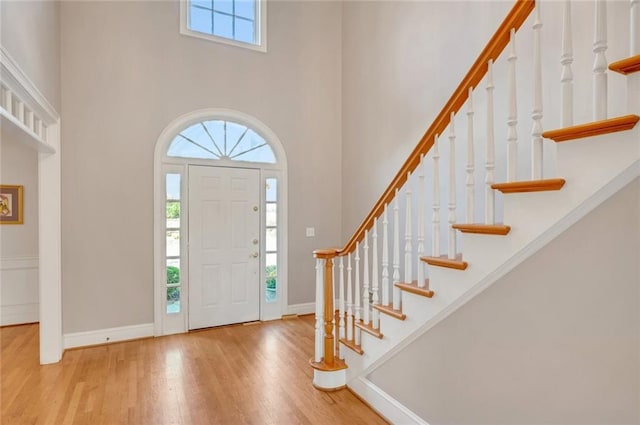 entrance foyer featuring a high ceiling, stairs, baseboards, and wood finished floors