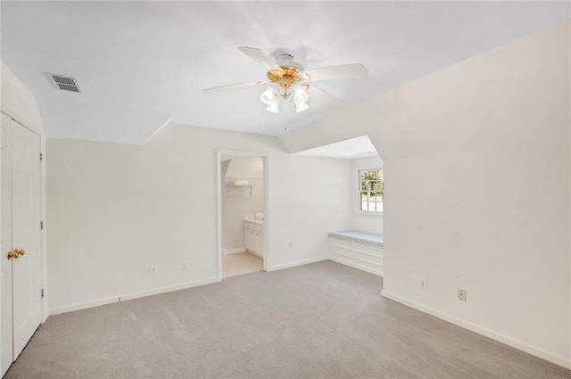 unfurnished bedroom with baseboards, visible vents, carpet floors, ensuite bath, and vaulted ceiling