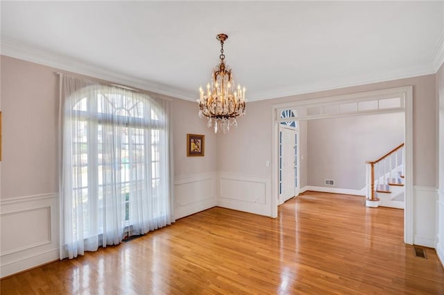 unfurnished dining area featuring light wood-style floors, a chandelier, stairs, and ornamental molding