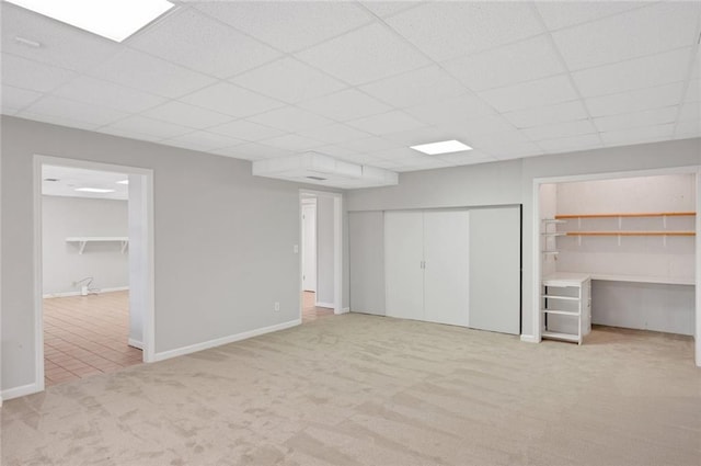 unfurnished bedroom with multiple closets, baseboards, a drop ceiling, and light carpet