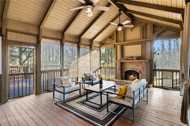 sunroom / solarium with ceiling fan, a wealth of natural light, a fireplace, and lofted ceiling with beams