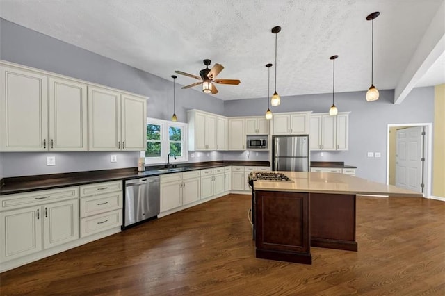 kitchen featuring appliances with stainless steel finishes, a sink, ceiling fan, dark wood-style floors, and a textured ceiling