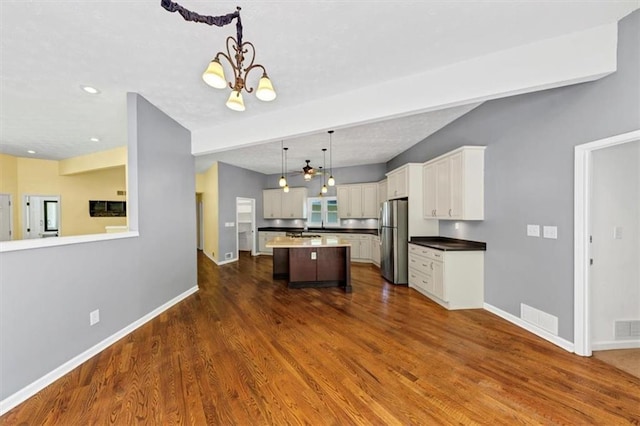 kitchen with freestanding refrigerator, a chandelier, baseboards, a center island, and recessed lighting