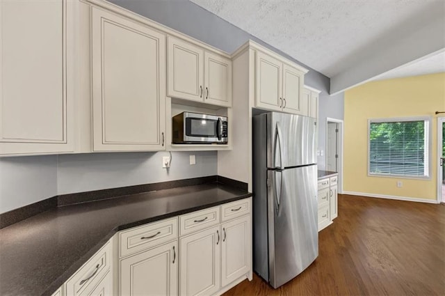 kitchen with stainless steel appliances, dark wood-style floors, dark countertops, baseboards, and a textured ceiling