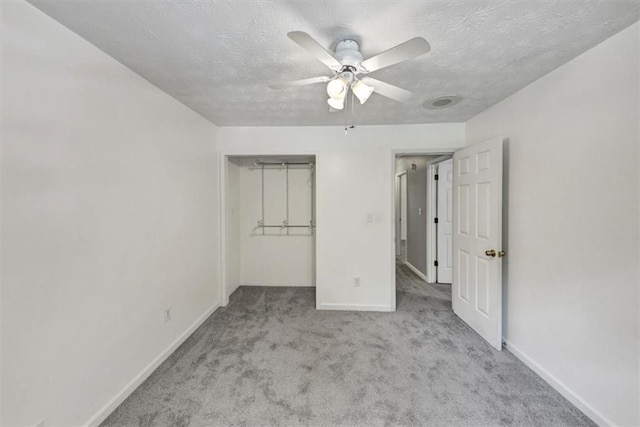 unfurnished bedroom with carpet flooring, baseboards, a textured ceiling, a closet, and a ceiling fan