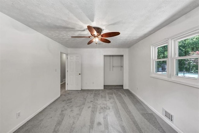 unfurnished bedroom with baseboards, carpet flooring, a closet, a textured ceiling, and ceiling fan