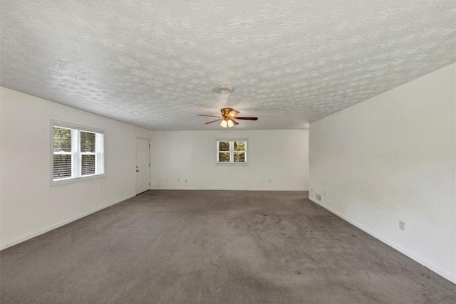 unfurnished room with healthy amount of natural light, carpet, ceiling fan, a textured ceiling, and baseboards