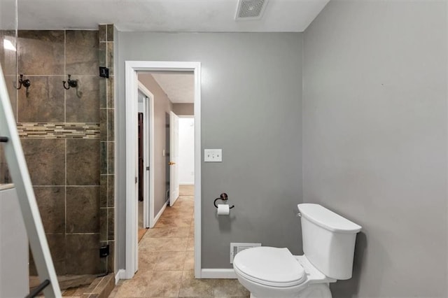bathroom featuring a shower stall, toilet, tile patterned flooring, and baseboards