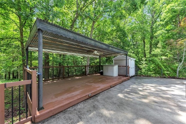 deck featuring a shed, an outbuilding, a view of trees, and a carport