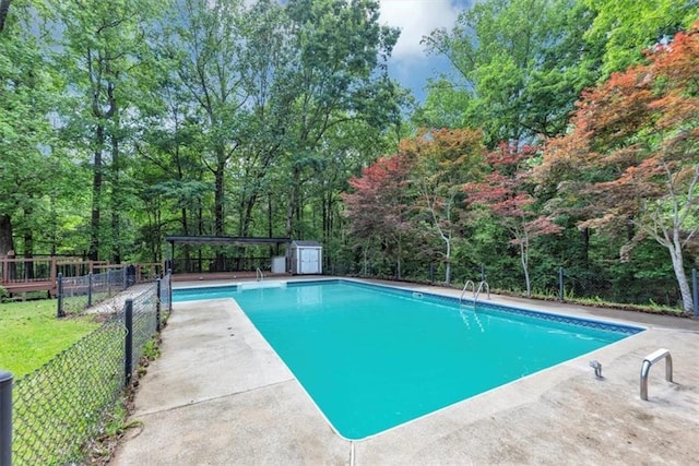 view of swimming pool featuring fence, a storage unit, and an outdoor structure
