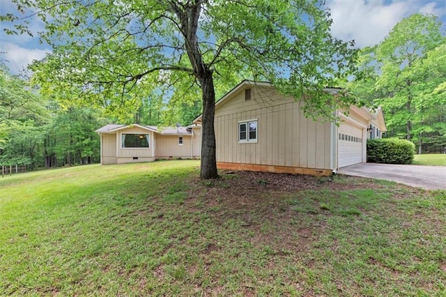 view of side of home featuring a lawn, driveway, and a garage