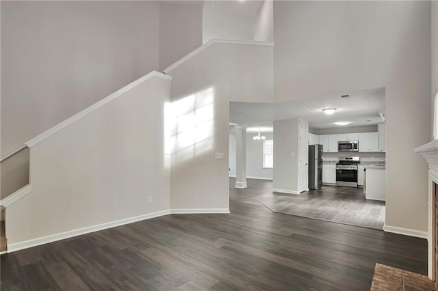 unfurnished living room featuring dark hardwood / wood-style flooring, a towering ceiling, and a fireplace