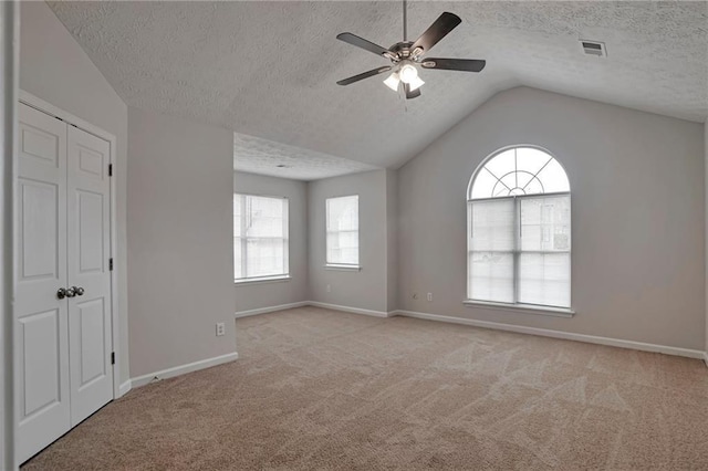 unfurnished bedroom featuring vaulted ceiling, ceiling fan, light carpet, and a textured ceiling