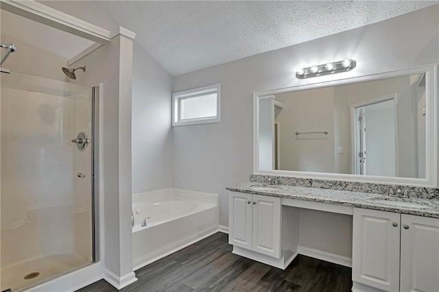 bathroom featuring independent shower and bath, vanity, wood-type flooring, and a textured ceiling