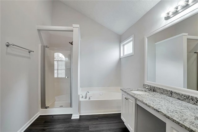 bathroom featuring vanity, a textured ceiling, vaulted ceiling, hardwood / wood-style flooring, and plus walk in shower