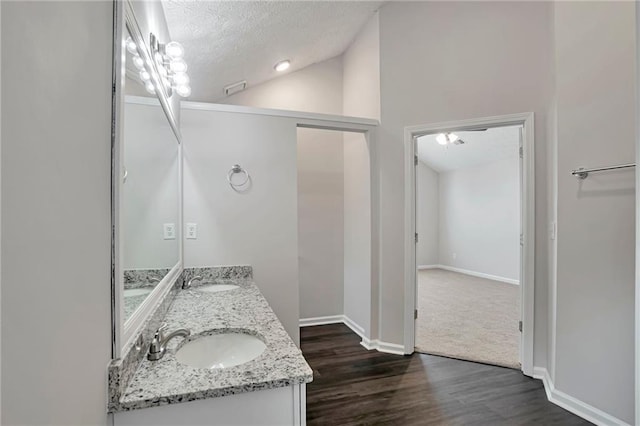 bathroom featuring hardwood / wood-style floors, vanity, a textured ceiling, and high vaulted ceiling