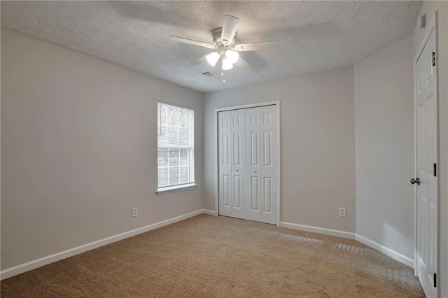 unfurnished bedroom with light carpet, a textured ceiling, a closet, and ceiling fan