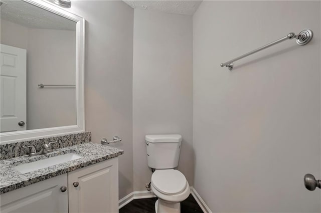 bathroom with vanity, a textured ceiling, and toilet