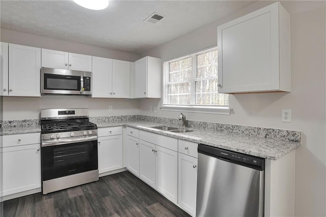 kitchen with stainless steel appliances, white cabinetry, dark wood-type flooring, and sink