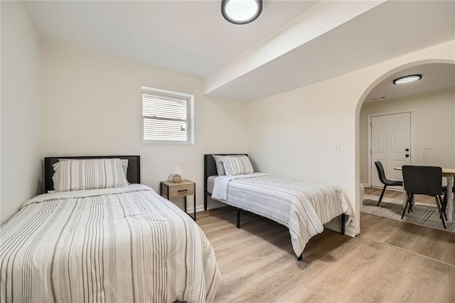 bedroom featuring light wood-style floors, arched walkways, and baseboards