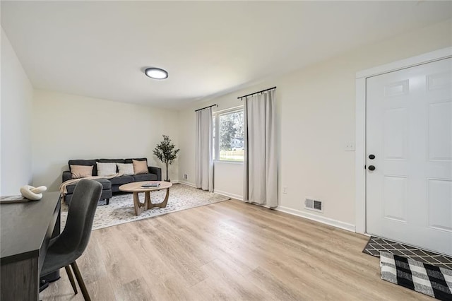 living area with visible vents, light wood finished floors, and baseboards
