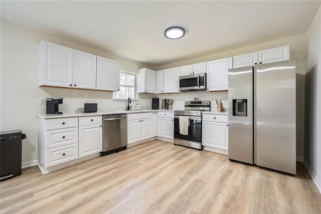 kitchen featuring a sink, light wood-style floors, light countertops, stainless steel appliances, and white cabinetry