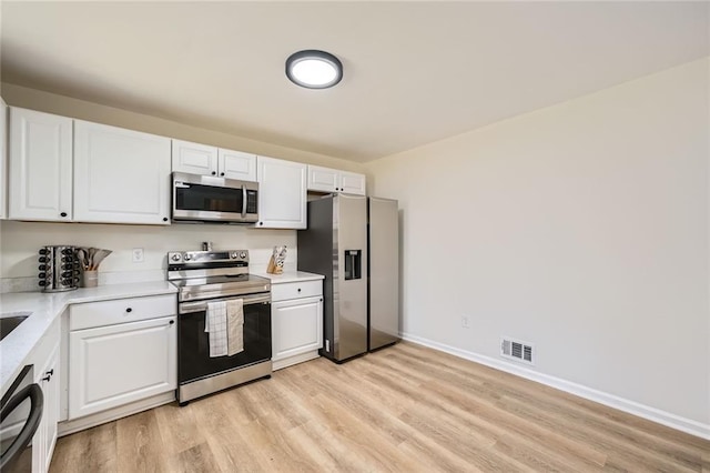 kitchen with light countertops, stainless steel appliances, white cabinetry, and visible vents